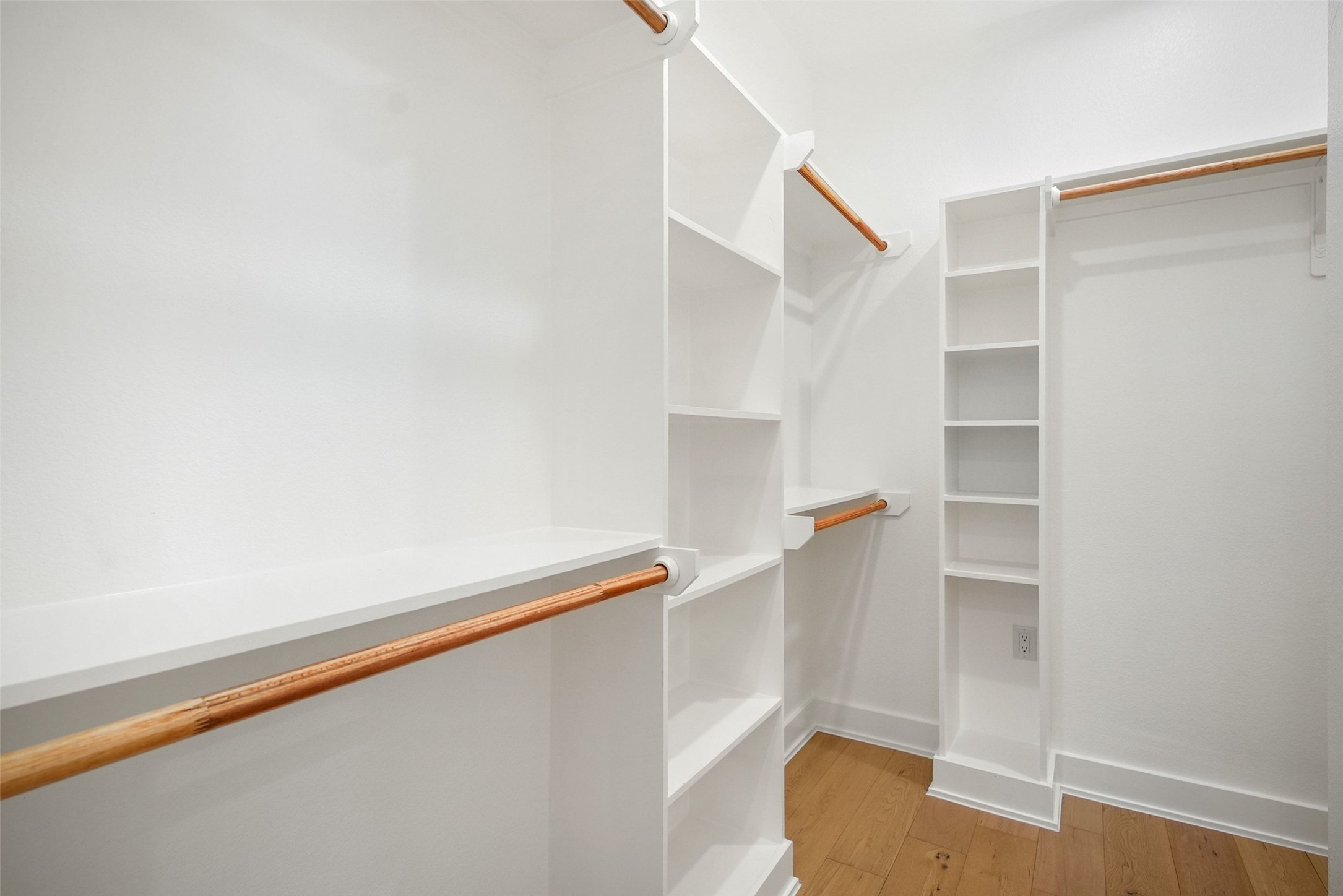 5109 Stone Gate Drive, Unit 2 Austin, TX 78721 - Photo 19 of 36 Walk-in closet featuring white built-in shelving, hanging rods, and wood-finish flooring