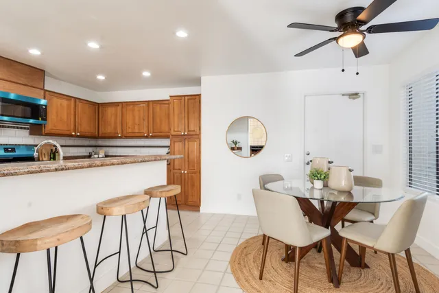 a kitchen with stainless steel appliances kitchen island granite countertop a dining table chairs and a refrigerator