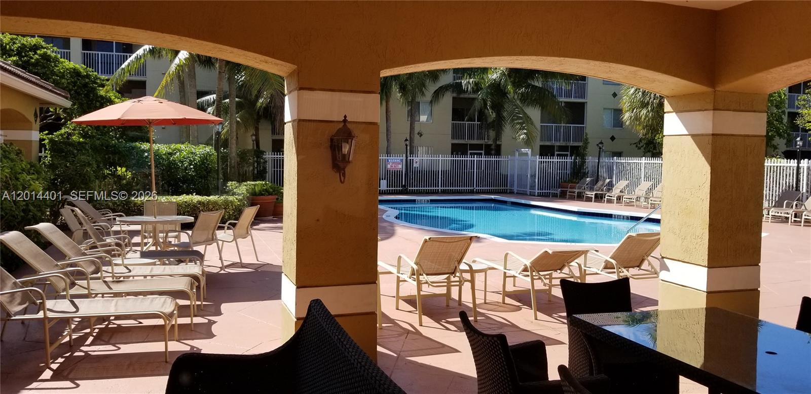 470 South Park Road, Unit 7110 Hollywood, FL 33021 - Photo 16 of 18 a view of a patio with couches table and chairs under an umbrella with a fire pit
