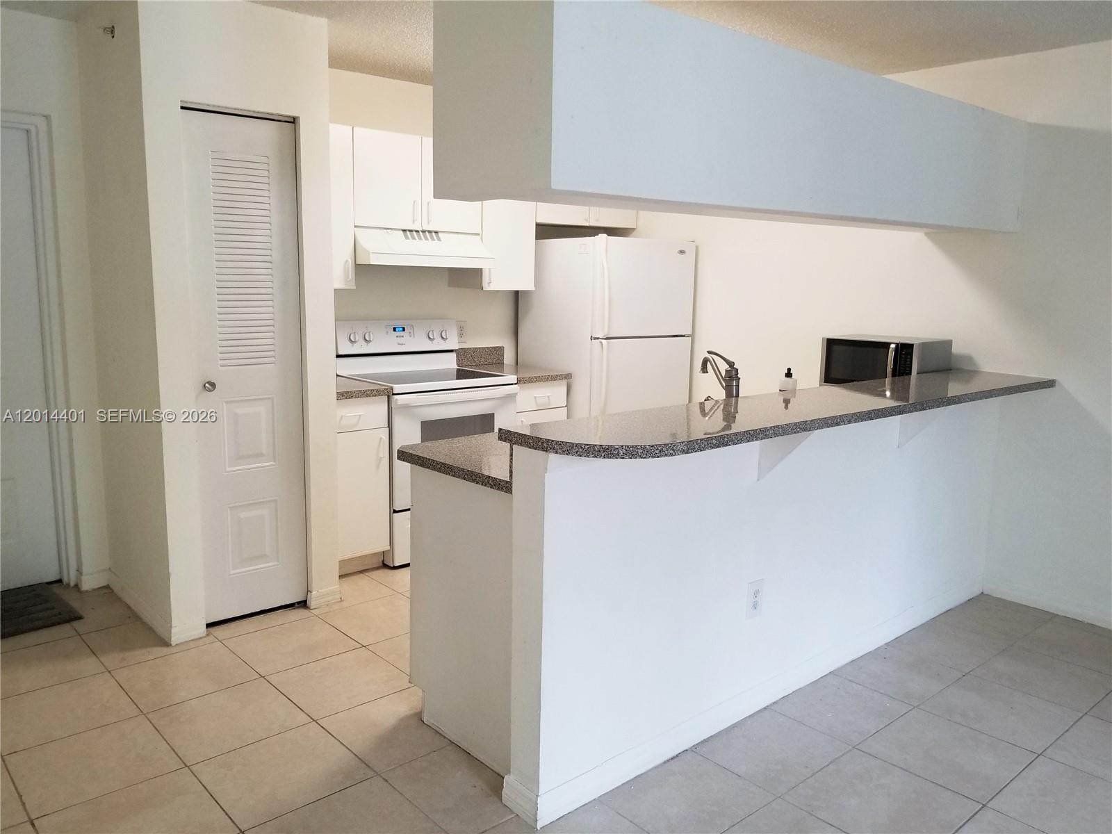 470 South Park Road, Unit 7110 Hollywood, FL 33021 - Photo 3 of 18 a kitchen with kitchen island granite countertop a sink a stove a refrigerator and white cabinets