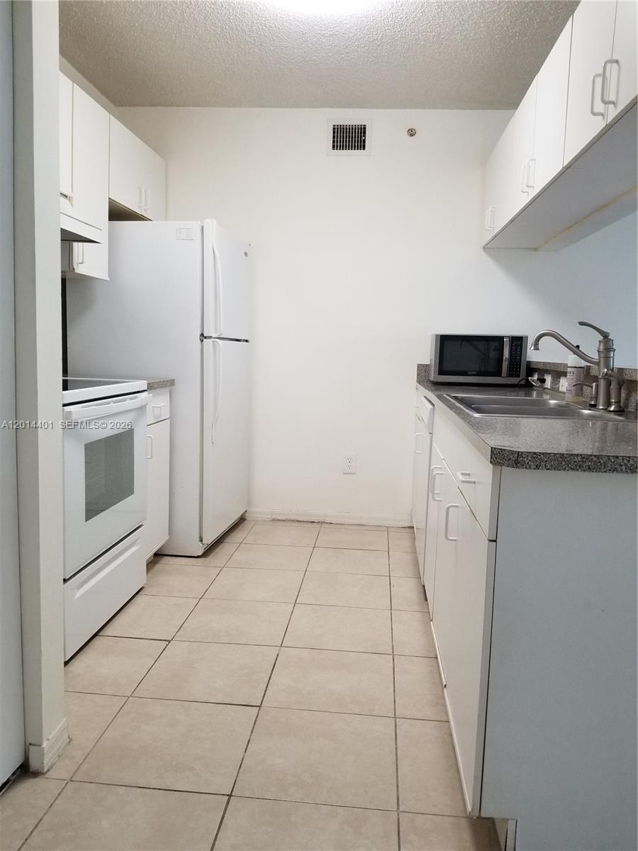 470 South Park Road, Unit 7110 Hollywood, FL 33021 - Photo 6 of 18 a kitchen with white cabinets a refrigerator and a stove top oven