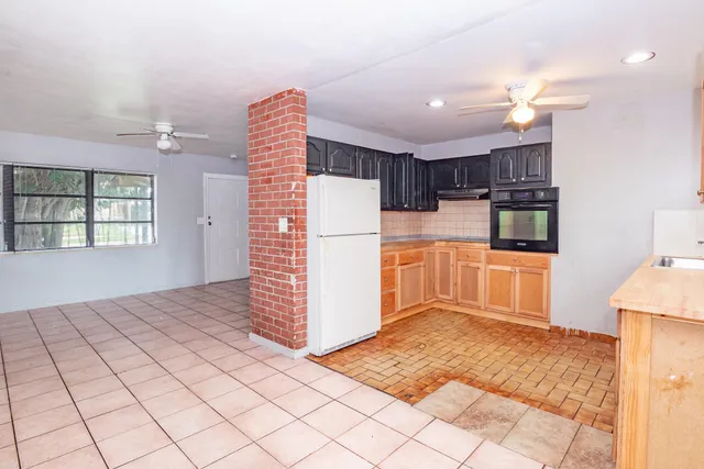 a kitchen with kitchen island granite countertop a refrigerator and a sink