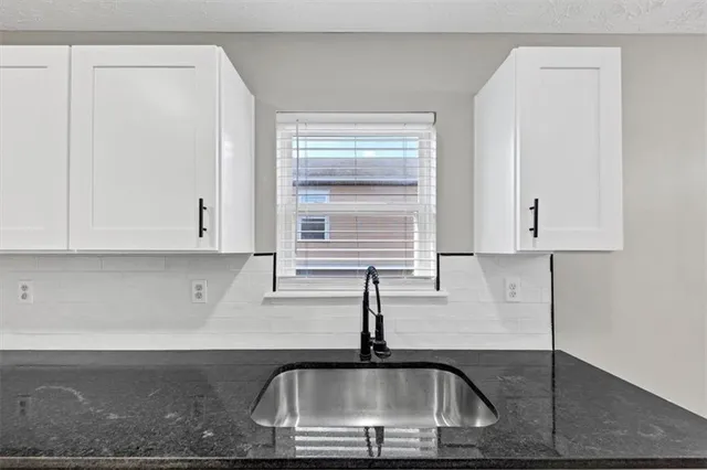 a kitchen with granite countertop a sink and white cabinets