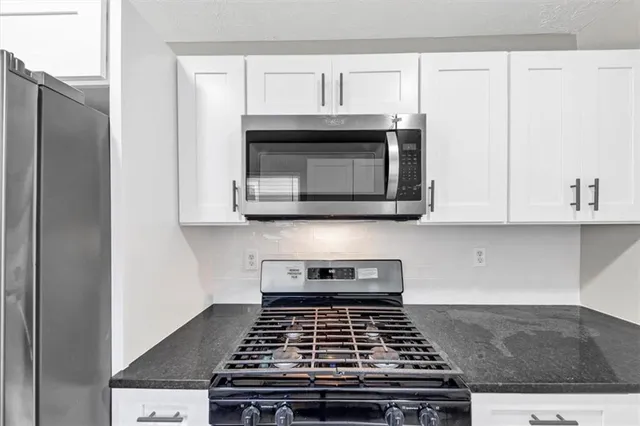 a kitchen with granite countertop a stove and a microwave