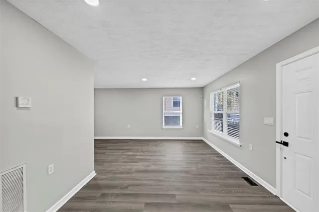 a view of an empty room with a window and wooden floor