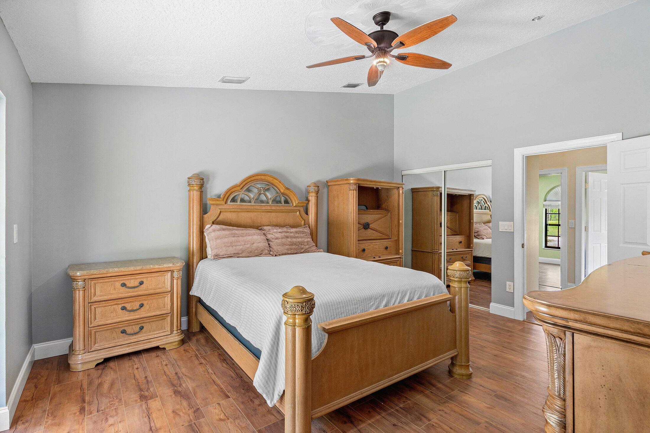 18142 43rd Road North Loxahatchee, FL 33470 - Photo 14 of 42 a bedroom with a bed and a chandelier