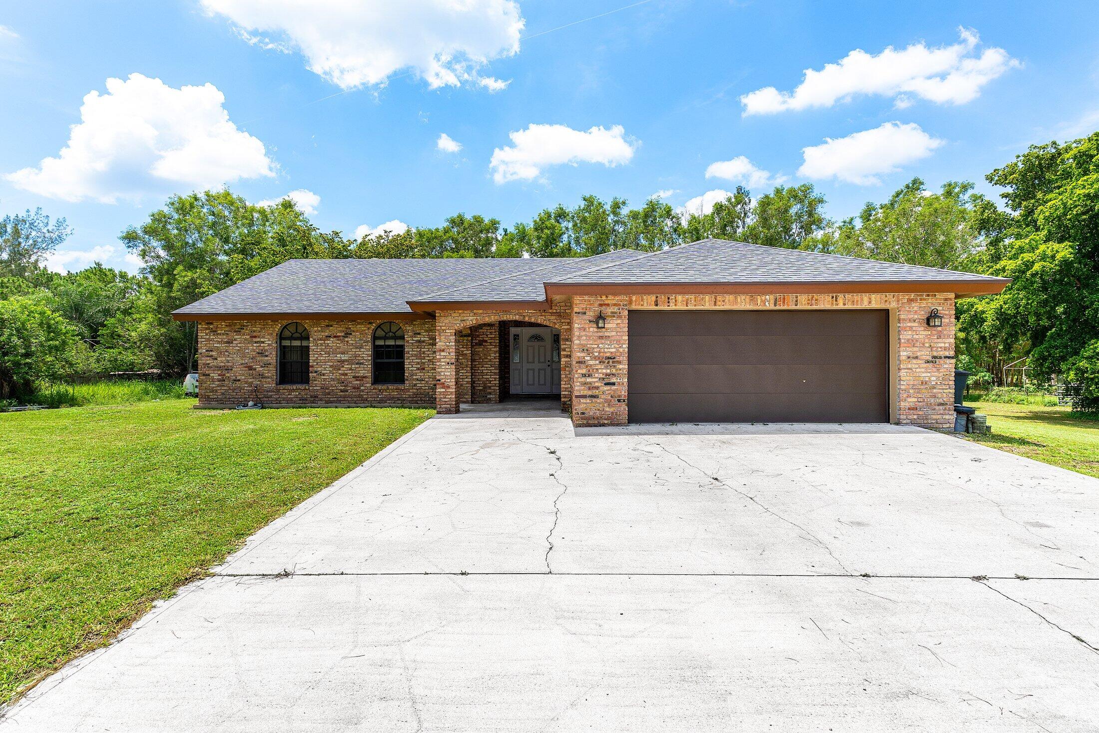 18142 43rd Road North Loxahatchee, FL 33470 - Photo 2 of 42 a front view of a house with a yard and garage