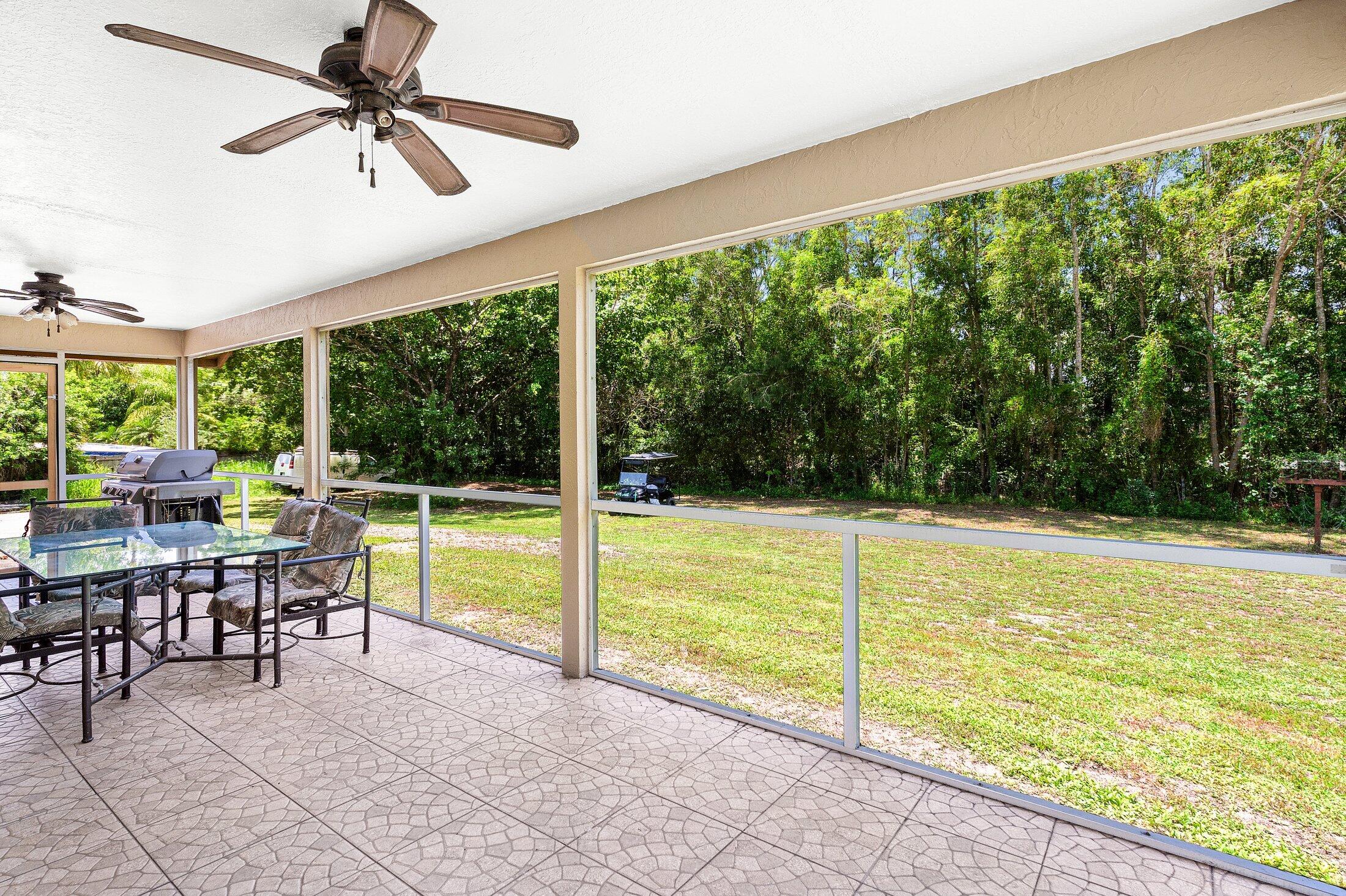 18142 43rd Road North Loxahatchee, FL 33470 - Photo 24 of 42 a view of a swimming pool with lawn chairs floor to ceiling window and an outdoor view