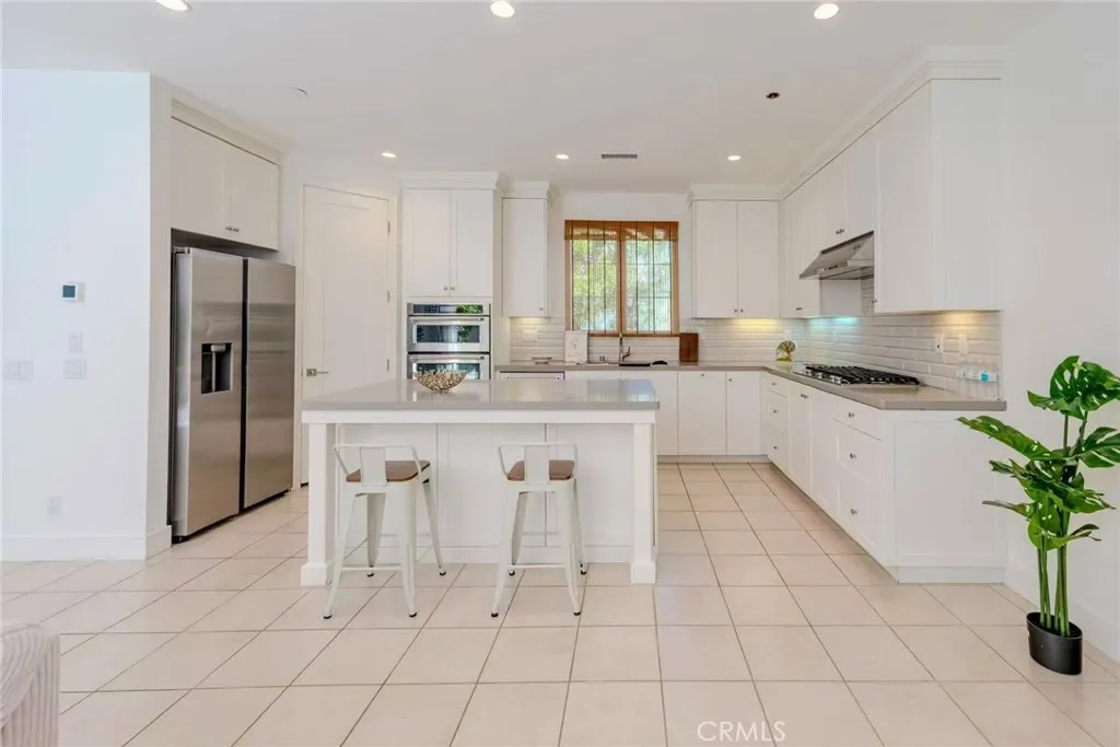 141 Dolci Irvine, CA 92606 - Photo 6 of 13 a kitchen with stainless steel appliances kitchen island granite countertop a refrigerator a sink a stove a dining table and chairs