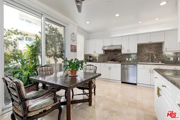a kitchen with granite countertop a table chairs microwave and cabinets