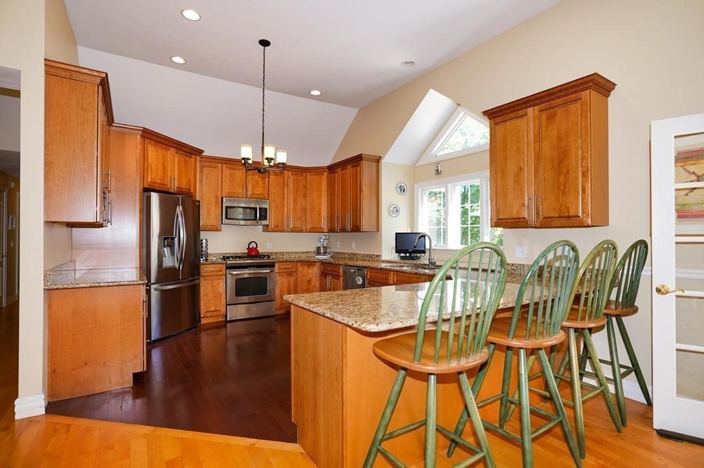 32 Frye Road Bolton, MA 01740 - Photo 7 of 35 a kitchen with stainless steel appliances granite countertop a refrigerator a sink dishwasher a stove and a dining table with wooden floor