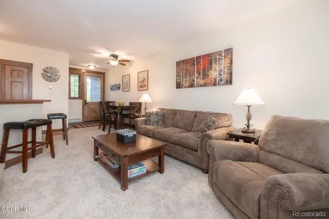 a living room with furniture and a dining table with wooden floor