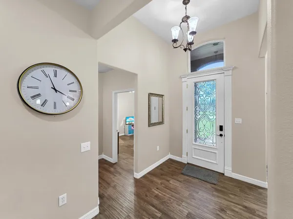 a view of a hallway with entryway wooden floor and a chandelier fan