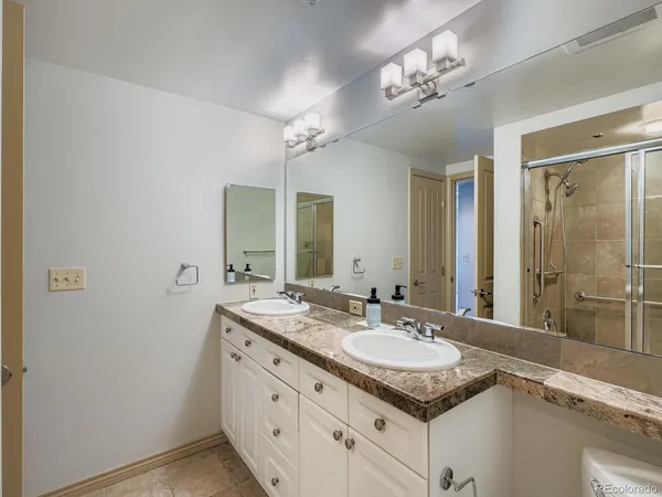 a bathroom with a granite countertop sink a large mirror and a shower