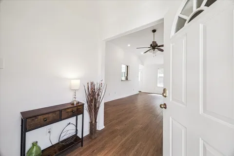 a view of a room with wooden floor and a ceiling fan