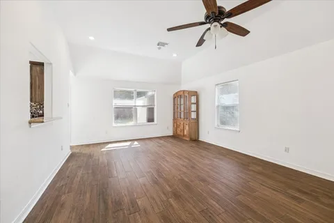 a view of empty room with wooden floor and fan