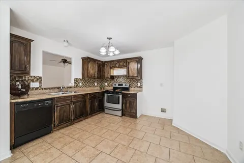a large kitchen with granite countertop a stove a sink and a microwave