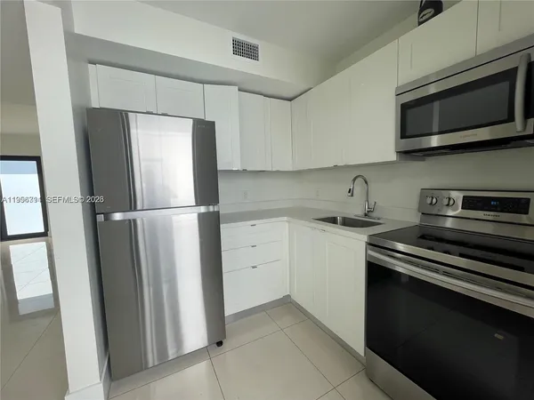 a kitchen with stainless steel appliances granite countertop white cabinets and a stove top oven
