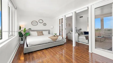 a bedroom with a bed and a large window with wooden floor