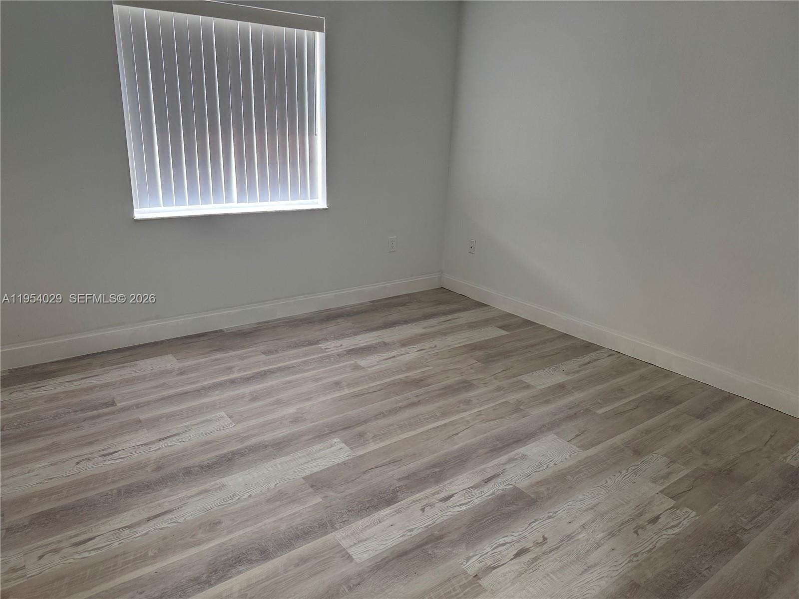 3940 Inverrary Boulevard, Unit 106A Lauderhill, FL 33319 - Photo 14 of 19 an empty room with wooden floor and windows