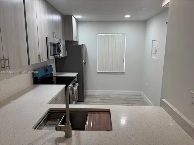 a view of a kitchen with a sink and a refrigerator