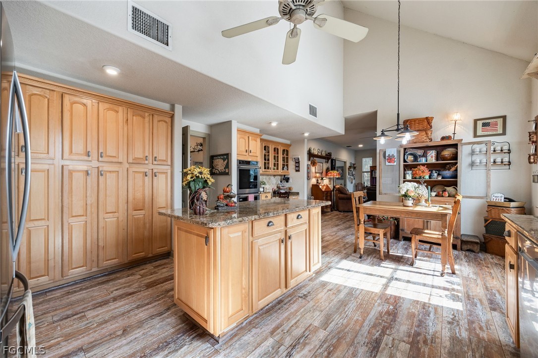 22800 North River Road Alva, FL 33920 - Photo 12 of 50 a kitchen with stainless steel appliances kitchen island granite countertop a table chairs and a wooden floor