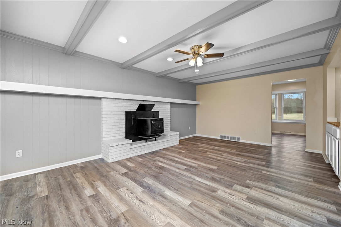 34725 Capel Road Columbia Station, OH 44028 - Photo 14 of 47 Living area featuring wood-finish flooring, white brick fireplace with a black wood-burning insert, coffered ceiling with recessed lighting, and a ceiling fan