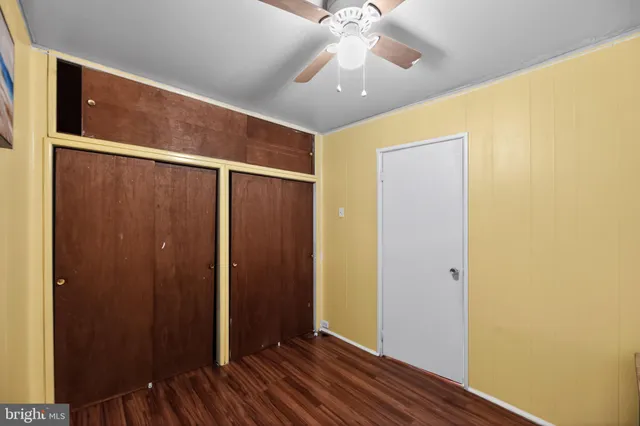 an empty room with wooden floor closet and fan