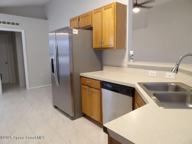 a kitchen with stainless steel appliances a sink a refrigerator and a counter top