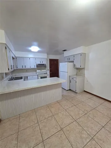 a large white kitchen with cabinets and a large window