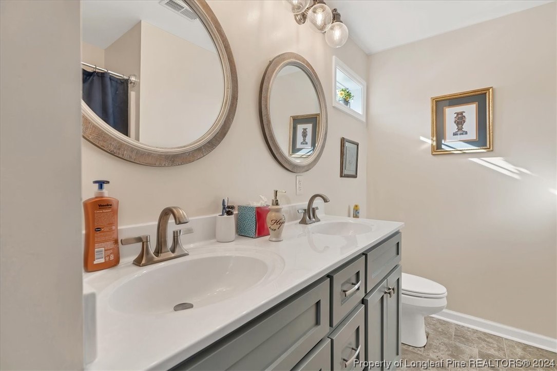 623 Hammonds Road Lumberton, NC 28360 - Photo 32 of 39 a bathroom with a toilet a sink and a mirror