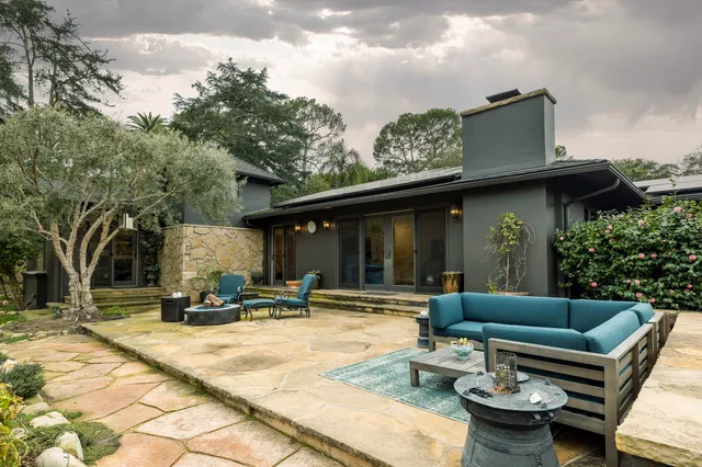 a view of a patio with couches table and chairs with wooden fence