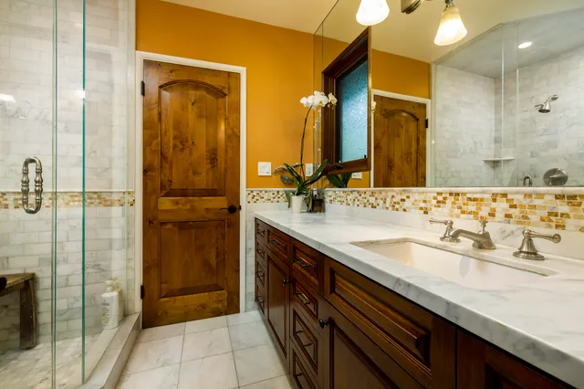 a bathroom with a granite countertop sink a mirror and a shower