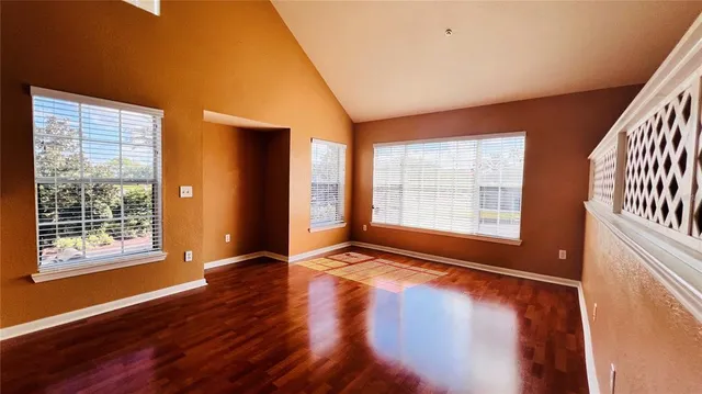 a view of an empty room with window and wooden floor