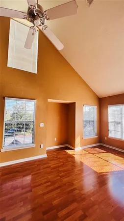 a view of empty room with wooden floor and fan