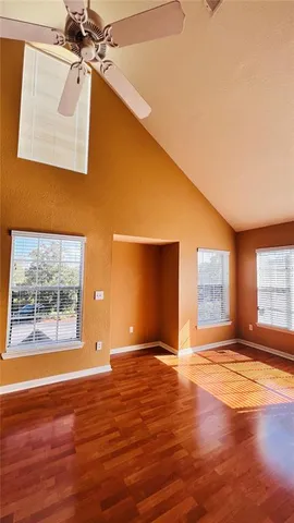 a view of empty room with wooden floor and fan