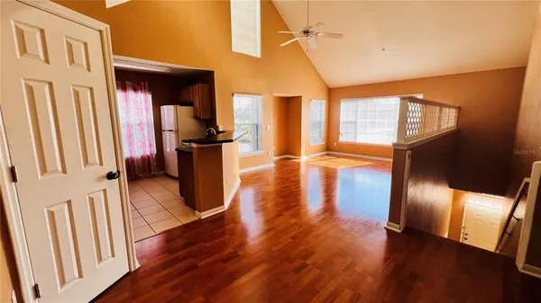 an empty room with wooden floor closet and windows