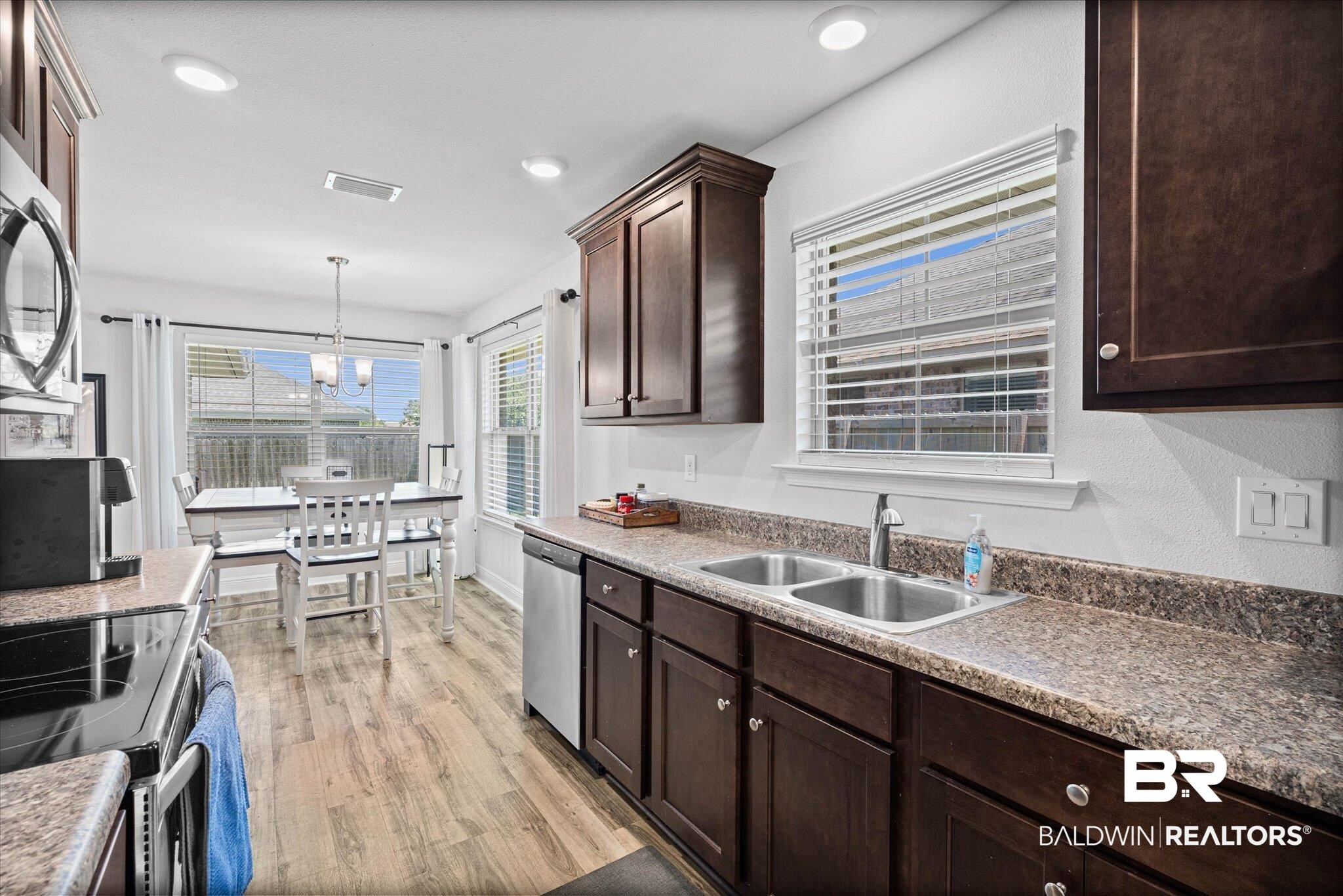 22420 Respite Lane Foley, AL 36535 - Photo 5 of 35 Kitchen featuring wood-finish flooring and dark wood cabinetry with light-colored countertops