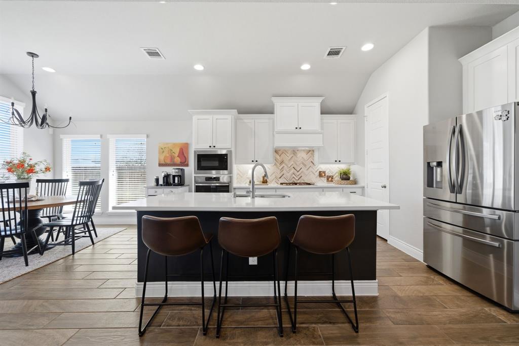 1121 Bantham Way Forney, TX 75126 - Photo 13 of 28 Stunning wood-tone island creates the perfect contrast to the white cabinets and backsplash.
