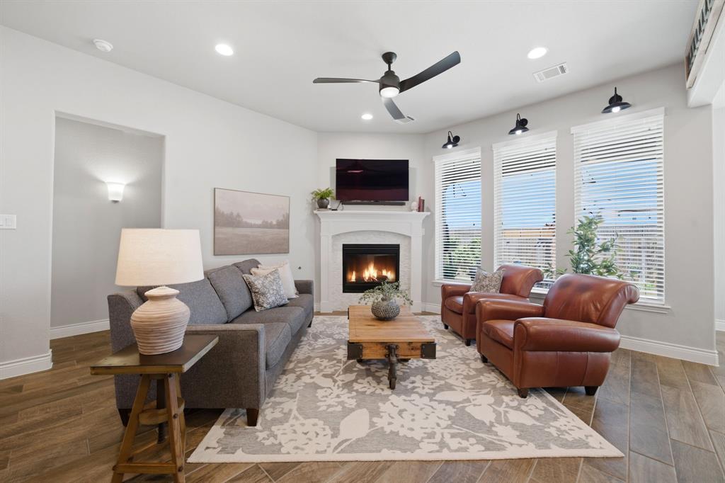 1121 Bantham Way Forney, TX 75126 - Photo 8 of 28 Wall of windows overlooking the backyard and creating natural light for the living area. Cozy up to the gas logs fireplace.