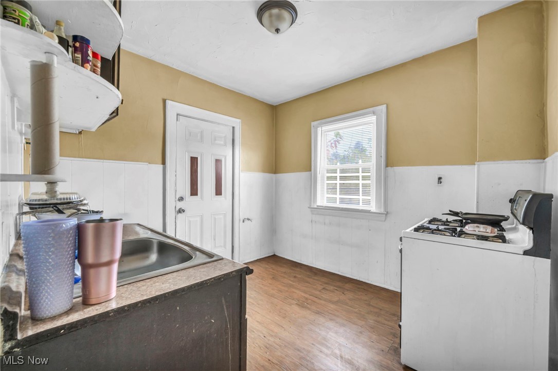 949 Rudyard Road Cleveland, OH 44110 - Photo 7 of 42 Kitchen with white gas range oven, a wainscoted wall, and wood finished floors