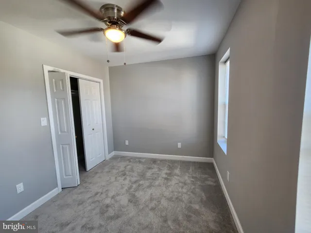 an empty room with closet and a chandelier fan