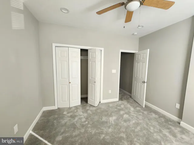 a view of an empty room and chandelier fan