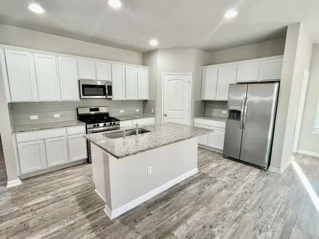 a kitchen with stainless steel appliances granite countertop a refrigerator sink and microwave