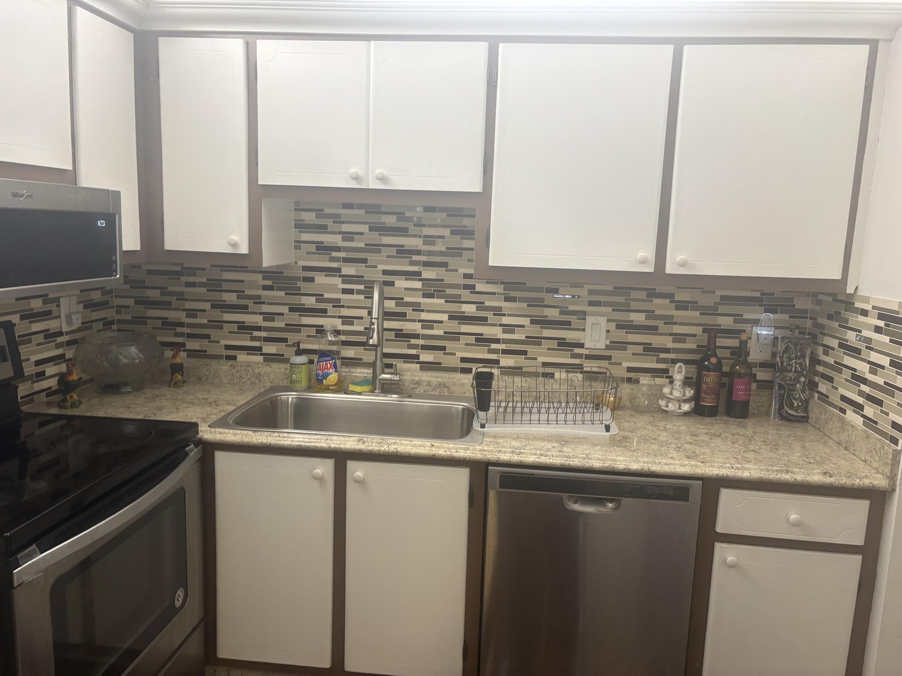 9355 Southwest 8th Street, Unit 225 Boca Raton, FL 33428 - Photo 7 of 21 a kitchen with stainless steel appliances granite countertop a sink and a microwave
