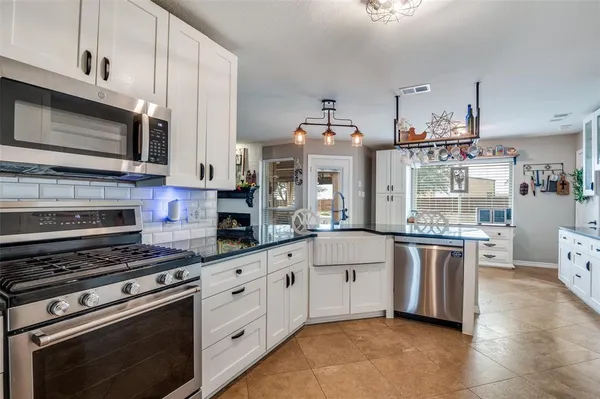 a kitchen with stainless steel appliances white cabinets a stove a sink and a microwave