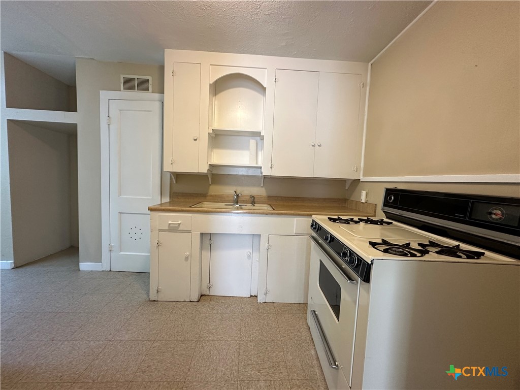 908 Pecan Street Seguin, TX 78155 - Photo 5 of 11 a kitchen with white cabinets and white appliances