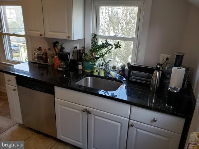 a kitchen with granite countertop white cabinets and window