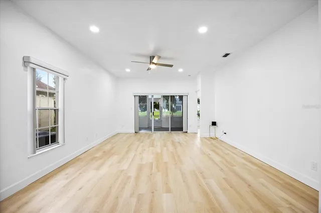 a view of an empty room with a window and a kitchen