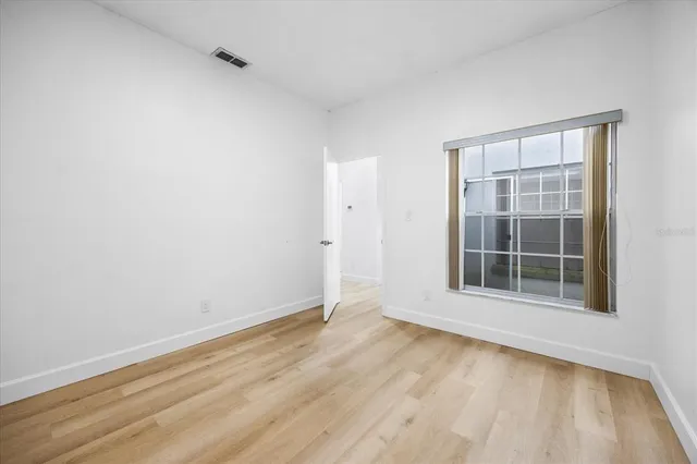 an empty room with wooden floor and windows